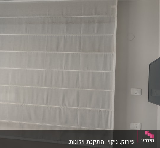 וילון לבן תלוי על קיר ליד טלוויזיה